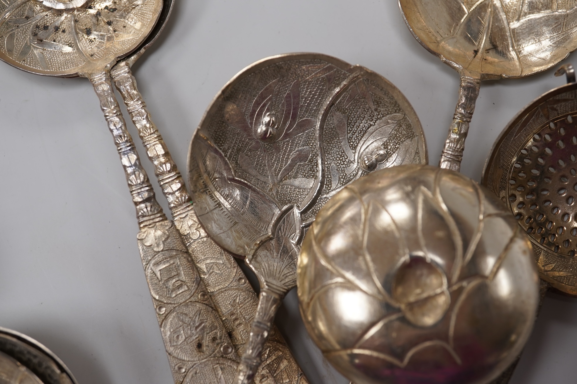 A set of twelve early 20th century Chinese Export white metal small spoons, maker LS, decorated with foliage and character mark, 10cm, a set of ten similar larger spoons, same maker, 12.3cm and another set a six similar